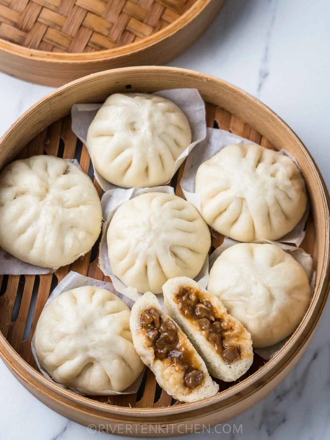 Steamed pork buns, split to show the filling
