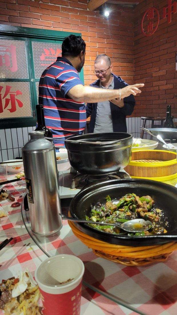 A wok of stir-fry with green chillies, arriving at the table