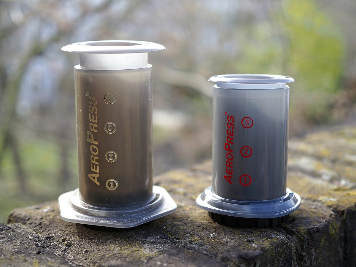 Two AeroPresses out in the field — the standard one and the smaller Go. A tube, a plunger, a filter cap, and nothing to break