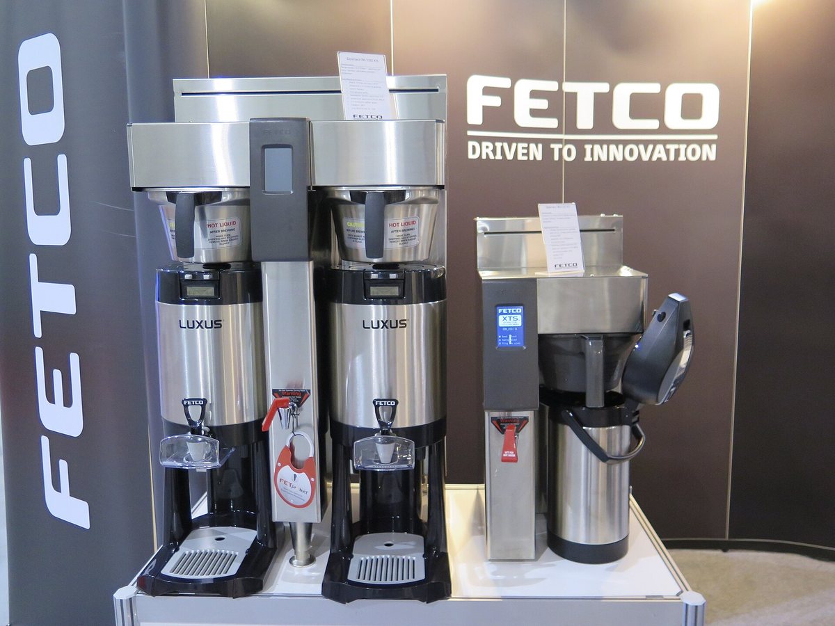 Fetco batch brewers over insulated Luxus dispensers, with an airpot alongside — volume coffee held hot without a hot plate anywhere
