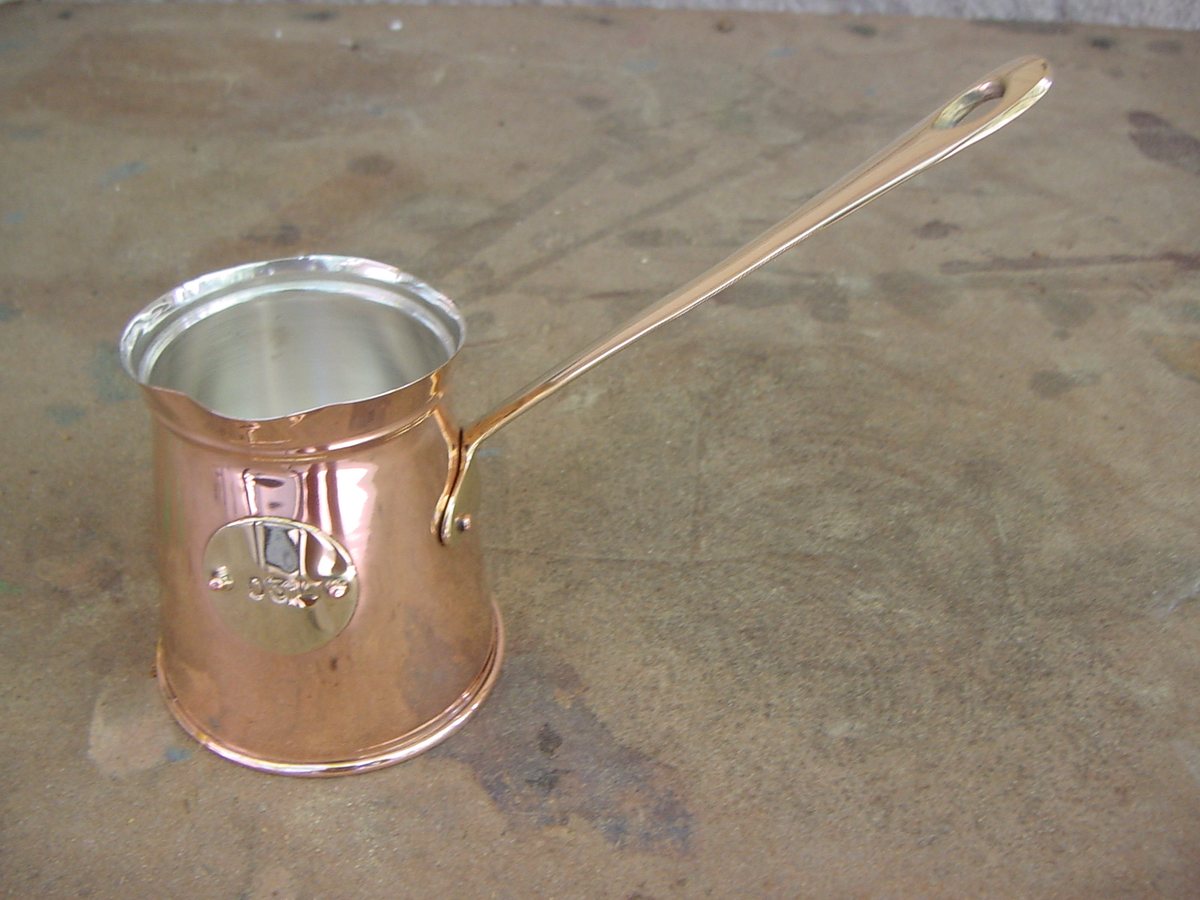 A copper cezve — small, tinned inside, and that long handle exists so you can pull it off the heat the instant the foam rises