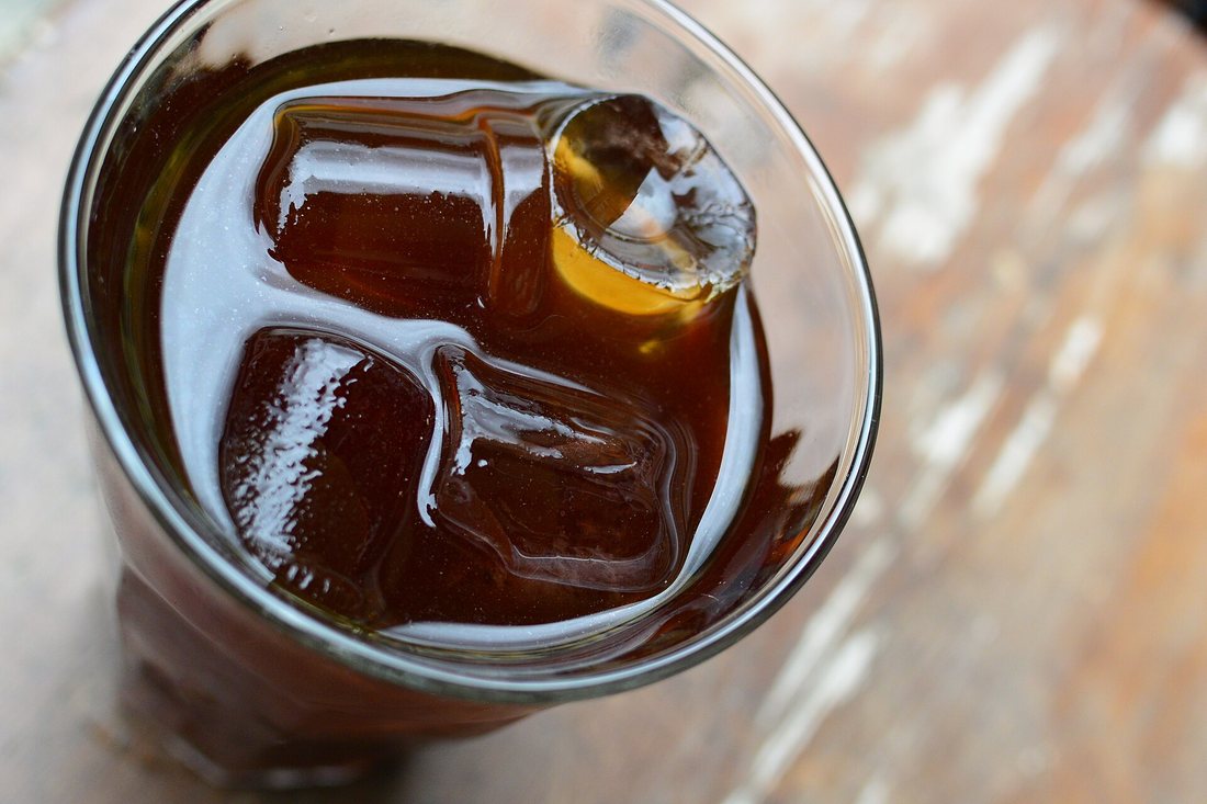 A glass of dark cold brew coffee over ice cubes, seen from above