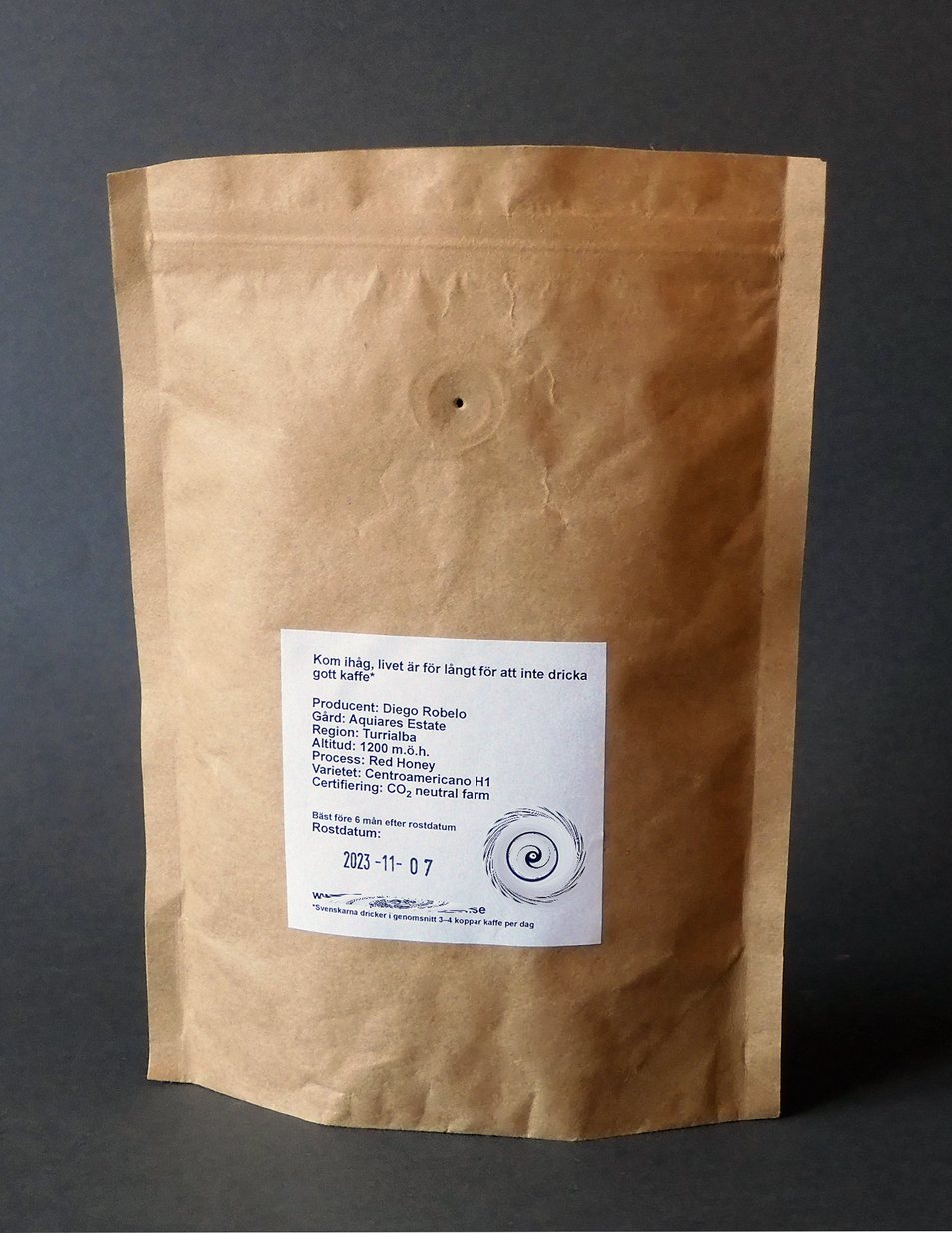 A kraft paper stand-up coffee pouch with a small white label and a one-way valve