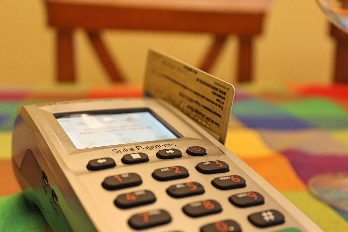 A card reader on a table with a bright striped cloth, a card inserted in its top and the screen lit