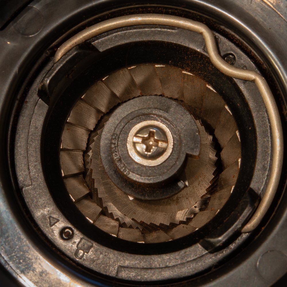 Looking down into a conical burr grinder: a ridged cone inside a ridged ring