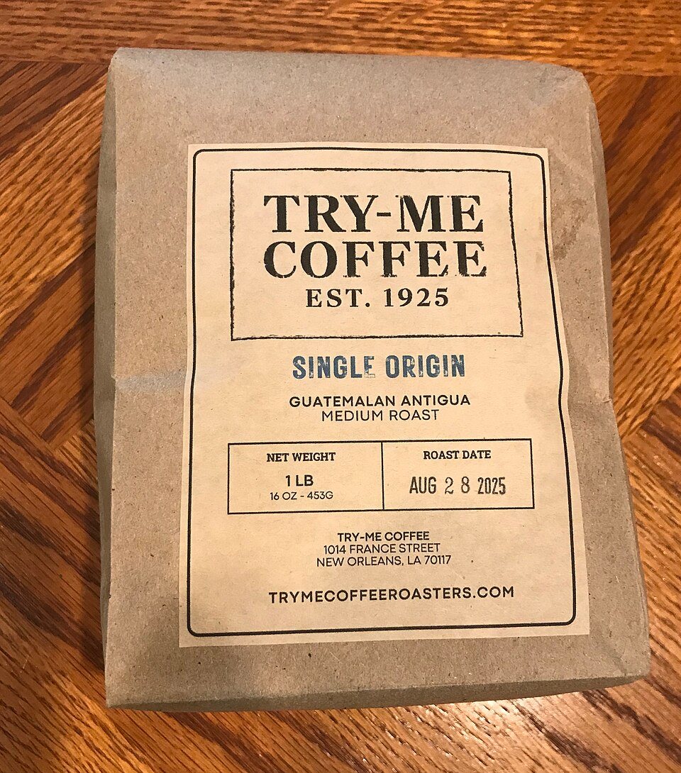 A kraft paper one-pound coffee bag with a printed label reading Try-Me Coffee, single origin Guatemalan Antigua medium roast, and a roast date stamped in a box