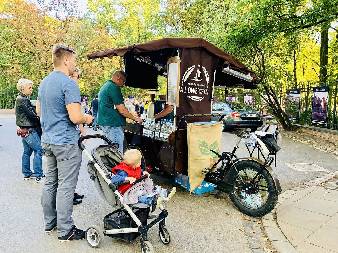 A coffee stall built on a cargo bicycle in a park, with customers waiting