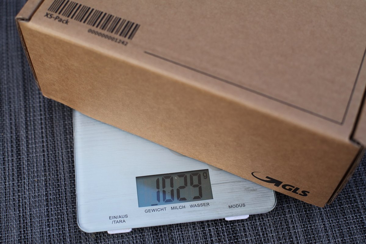 A cardboard parcel on a digital kitchen scale reading 1,029 grams