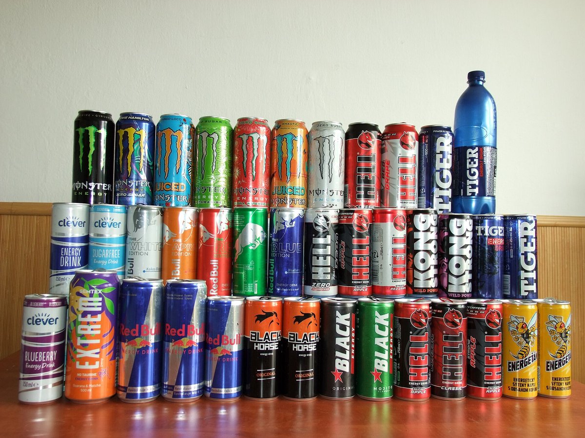 Rows of energy-drink cans of many brands stacked on a shelf