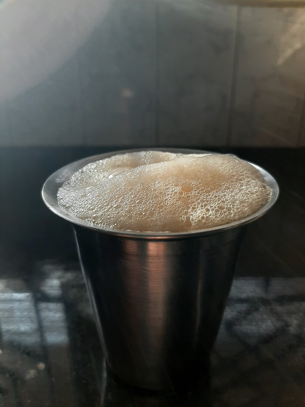 A steel tumbler of frothy, milky South Indian filter coffee, a speciality of Kumbakonam, Tamil Nadu