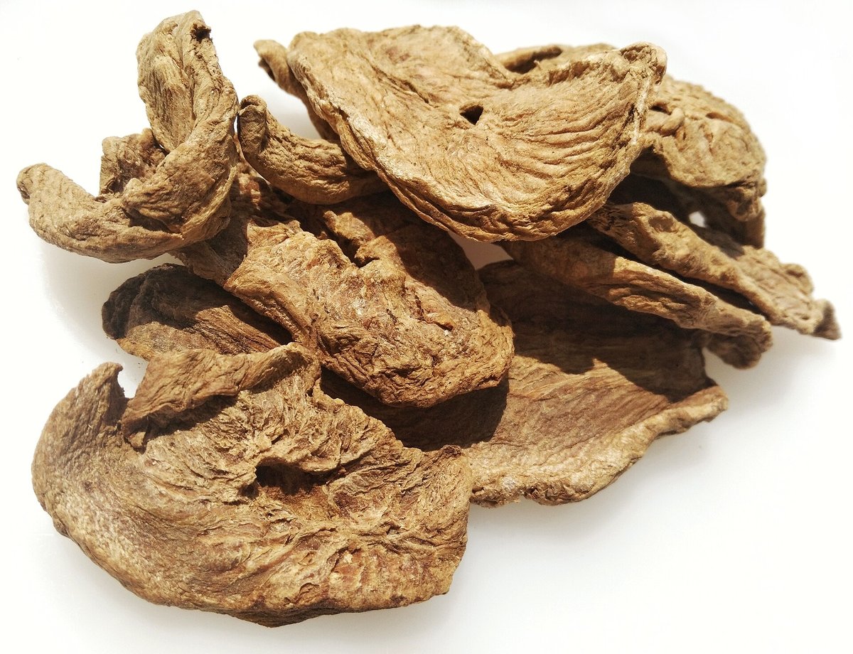 Dried pieces of chicory root, pale tan and twisted, piled on a white background