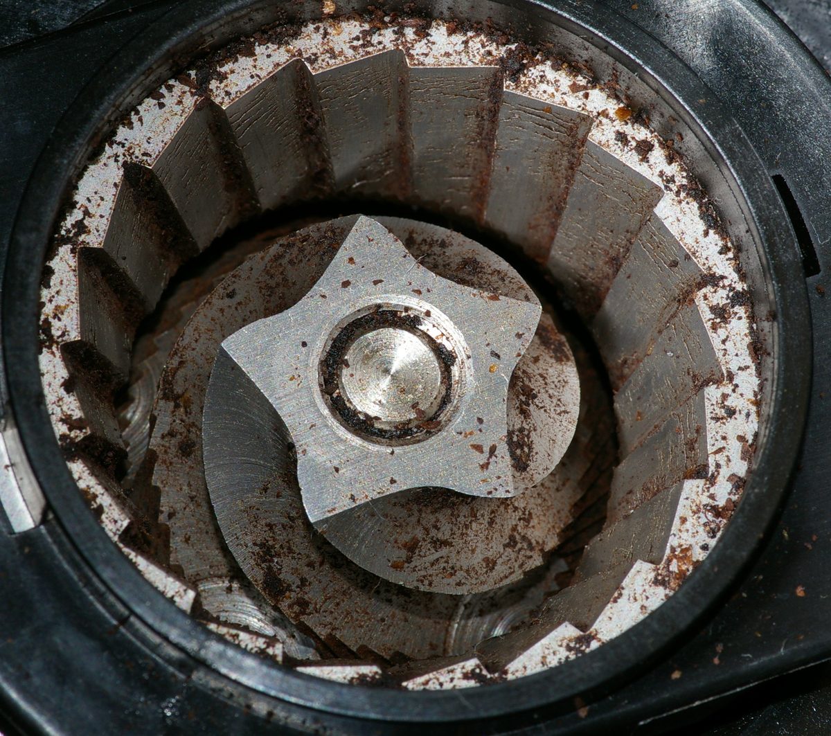 A burr grinder beside a portafilter — the burrs, not the boiler, are what decide whether a shot is even possible
