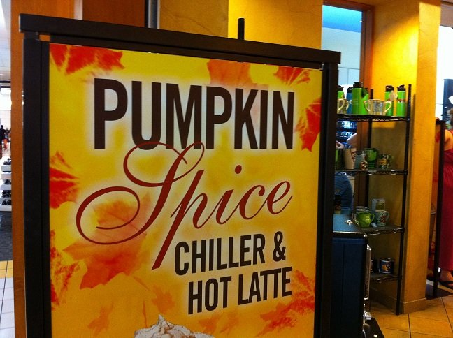 A sign in a café reading Pumpkin Spice Chiller and Hot Latte, in front of a counter