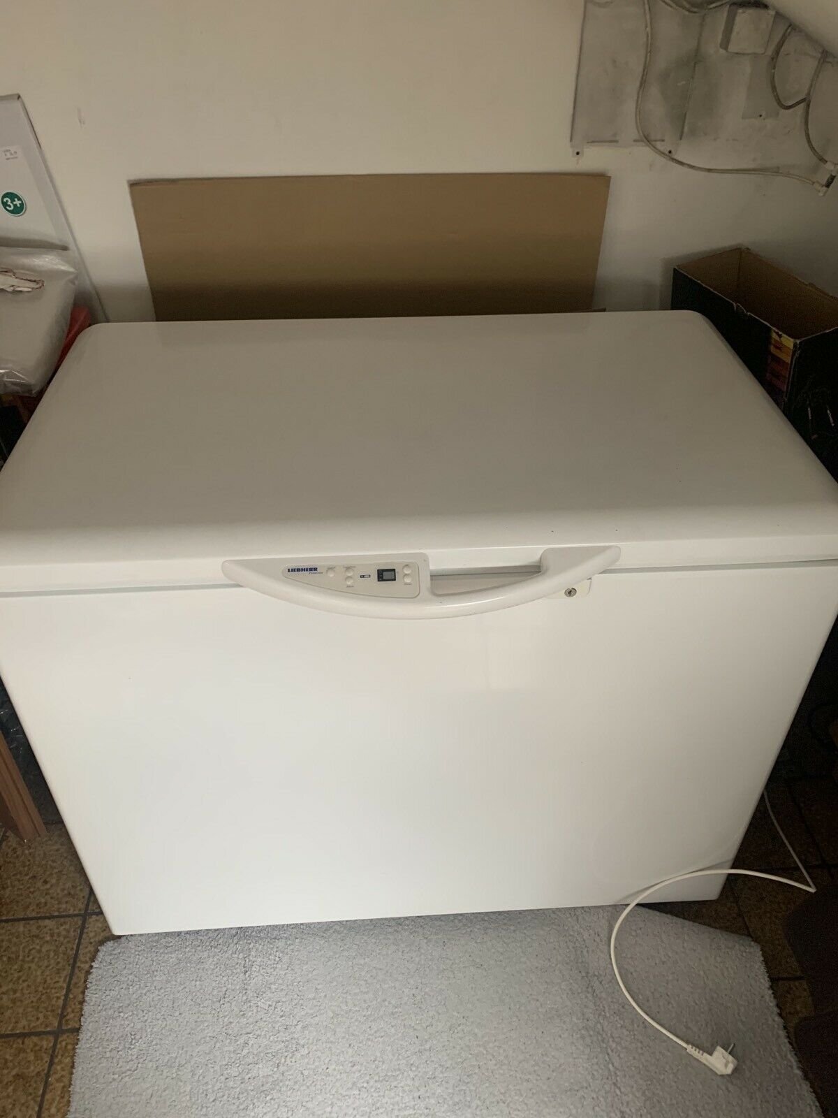 A white chest freezer standing against a wall in a utility room