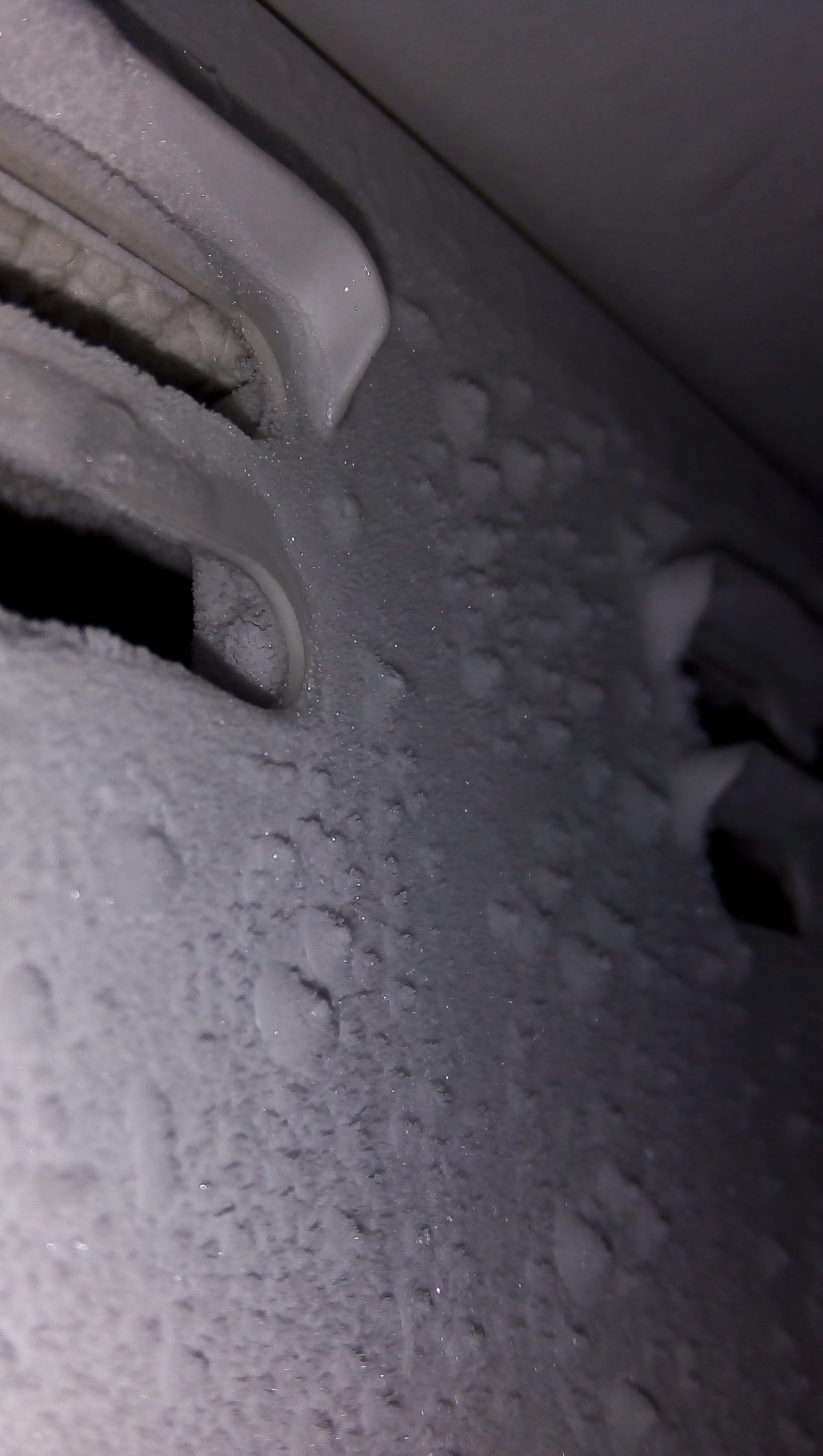 Frost and water droplets on the inside wall of a freezer compartment