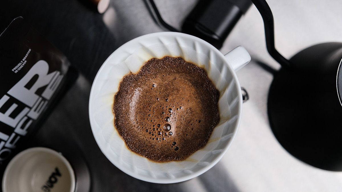 A pour-over cone blooming — fresh grounds swelling and releasing CO2 under the first pour of water