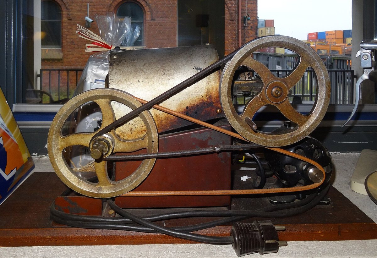 A drum roaster with its face off — belts, drive, and the drum itself. The idea is a century old and the geometry has barely moved