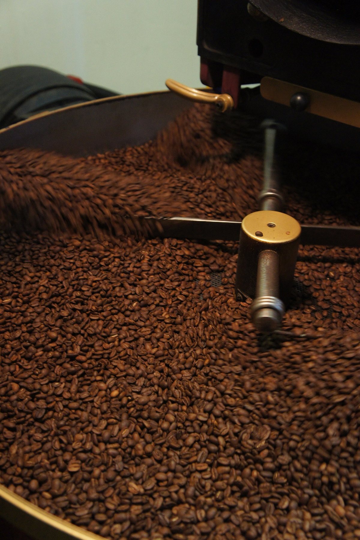 The drop. The roast ends the instant the beans leave the drum — and the cooling tray underneath has to pull the heat out fast, because a bean full of stored energy keeps roasting itself