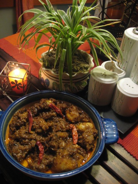A Goan pork vindaloo — dark, close-textured, with whole dried red chilies through it