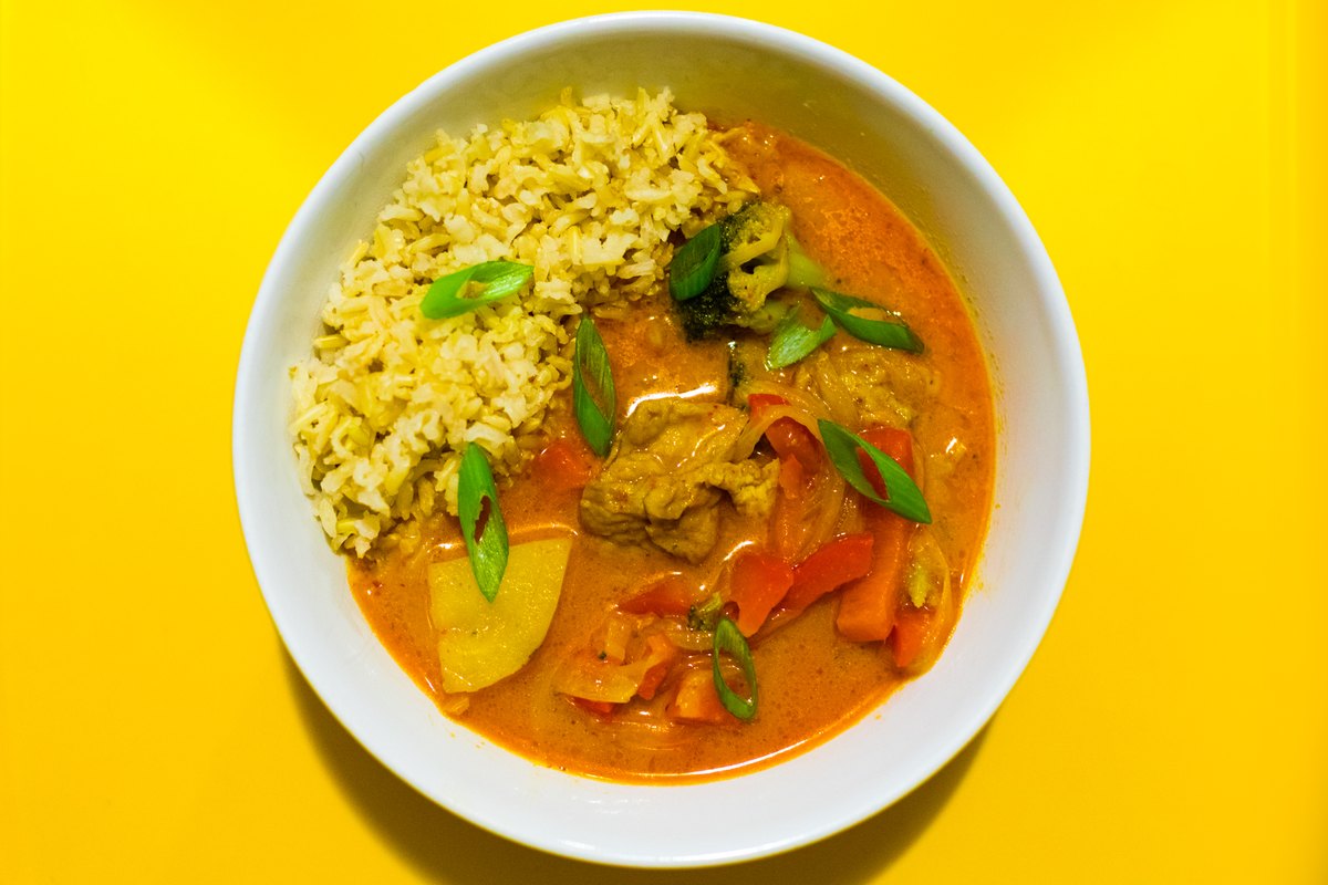 A bowl of red curry with chicken, served with rice