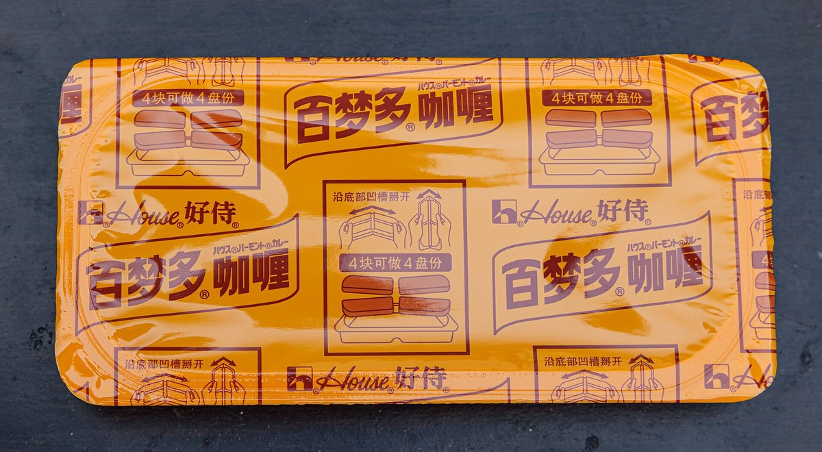 A curry roux block in its wrapper — solid fat, flour and spice, scored into cubes like a chocolate bar