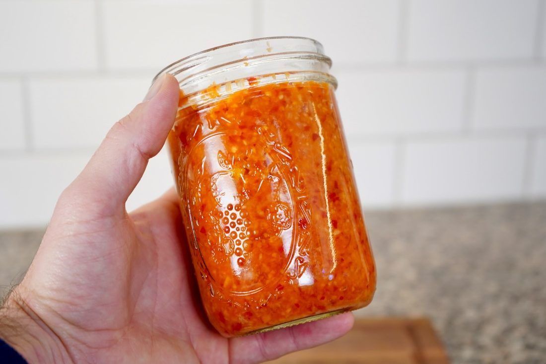 A jar of fermented chile mash. Fermentation turns the raw green sharpness of fresh chile into something round and fruity that vinegar cannot reach