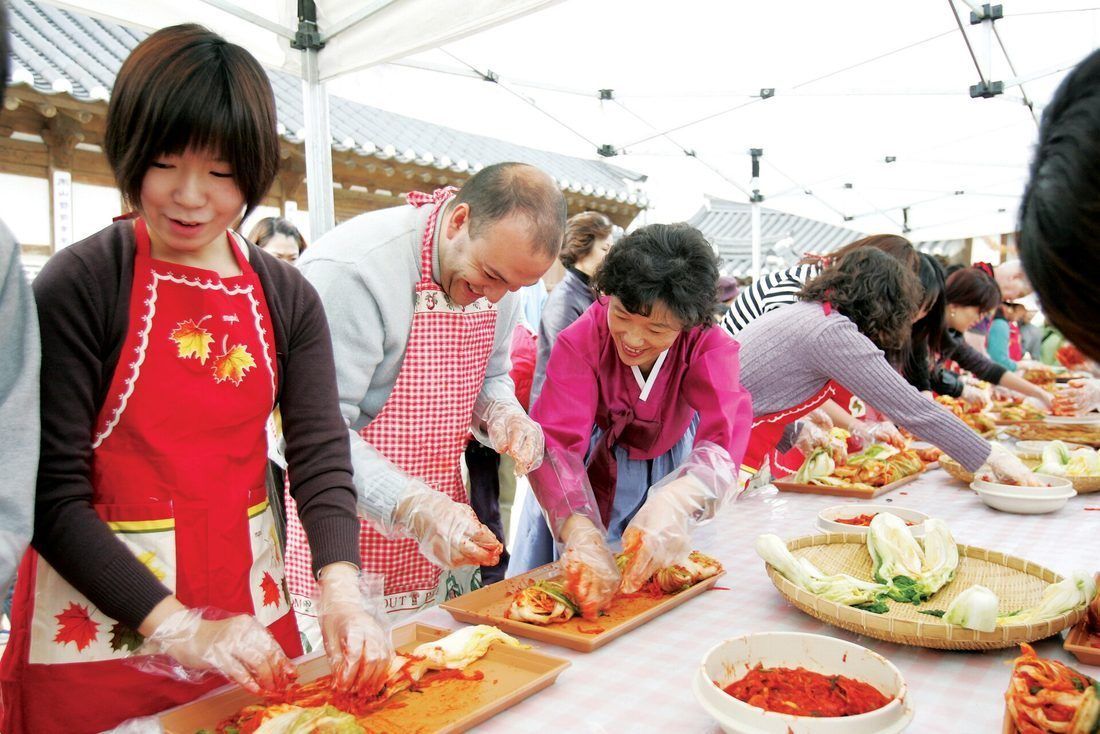 Coating cabbage with the seasoning paste, by hand and in gloves — the paste has to reach every leaf