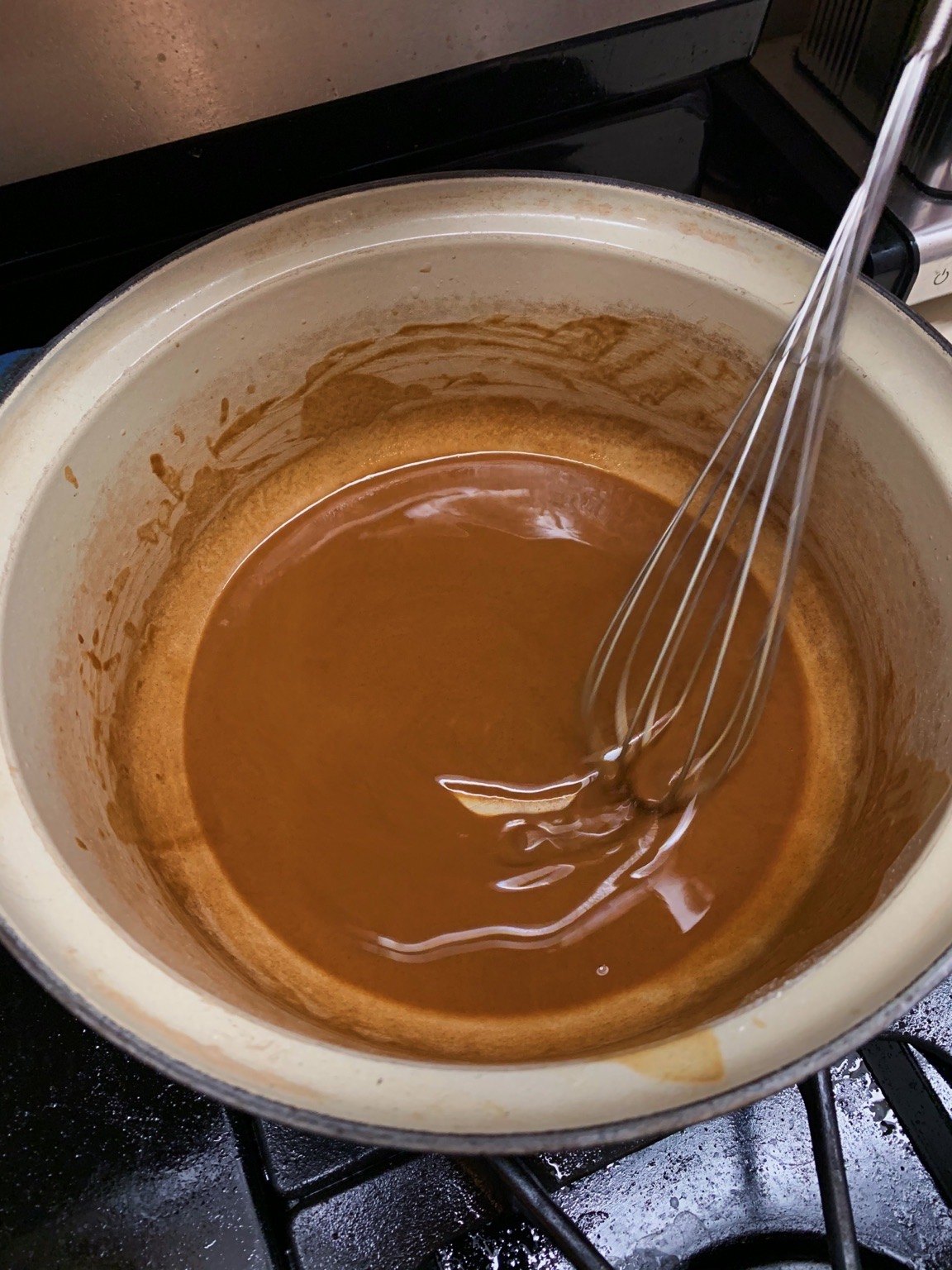 A brown roux being whisked — around the peanut-to-copper stage, well short of chocolate