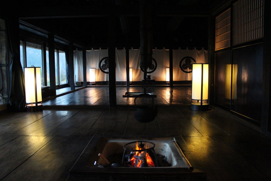 An irori alight in a darkened room. There is no food in this frame — but this is the environment the food sat in for hours, and the reason it tasted the way it did