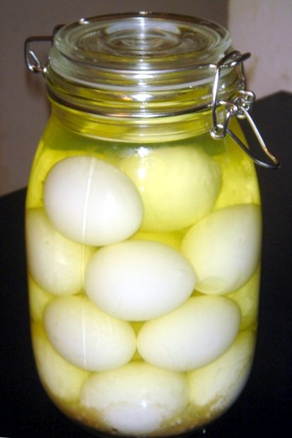 A glass jar of whole pickled eggs in brine