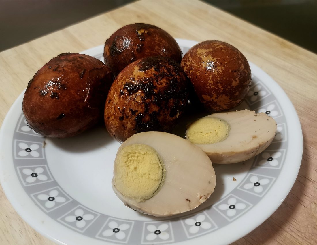 Telur pindang — eggs stained a deep russet brown, one peeled to show the marbling