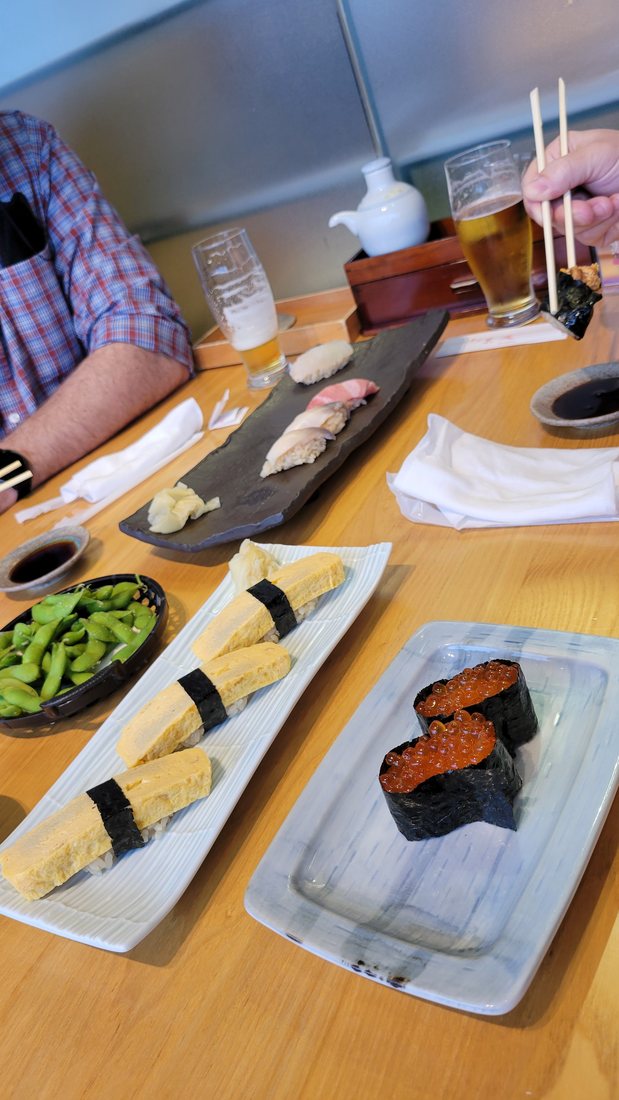 The last thing I ate on this trip: nigiri on a slate board, tamago nigiri, ikura gunkan-maki, edamame and a beer