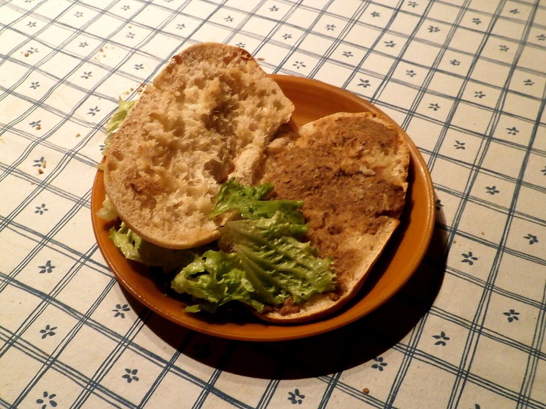 Dark rillettes de Tours spread on split bread rolls on a terracotta plate with lettuce
