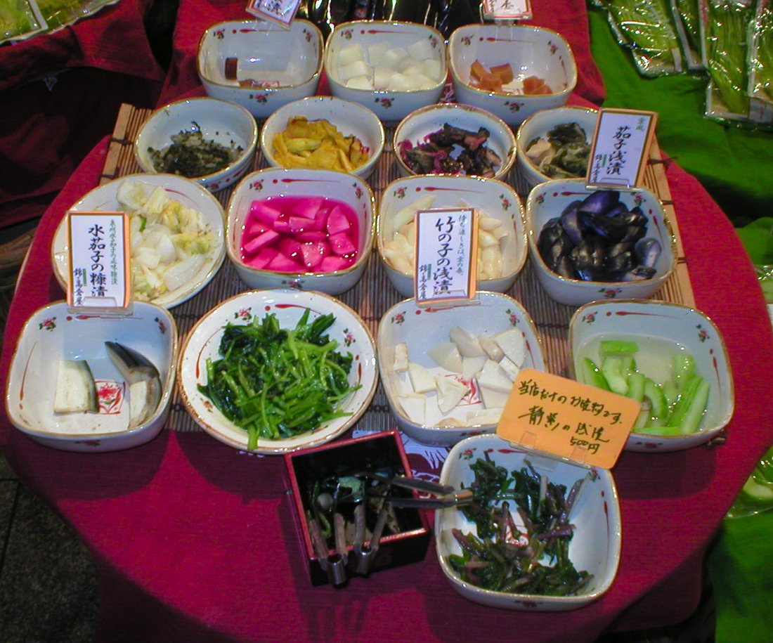 A spread of labelled tsukemono samples. This is the page's whole argument in one photograph: not one pickle with variations, but many different crafts sharing a shelf and an English word