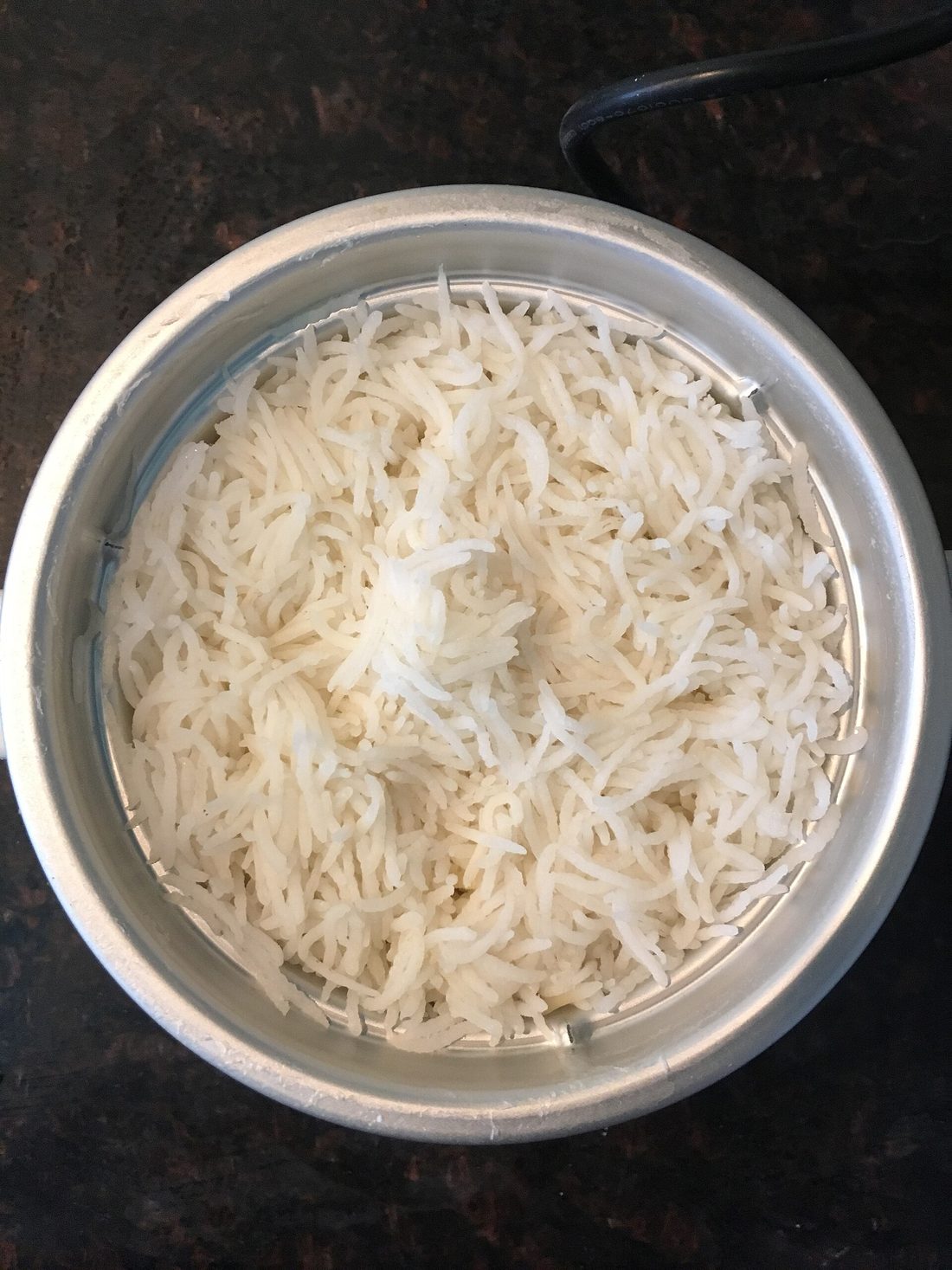 A pot of fluffy long-grain white rice, lid just lifted, steam rising, each grain separate