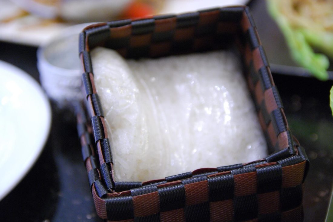 Sticky glutinous rice steaming in a traditional woven bamboo basket over a pot