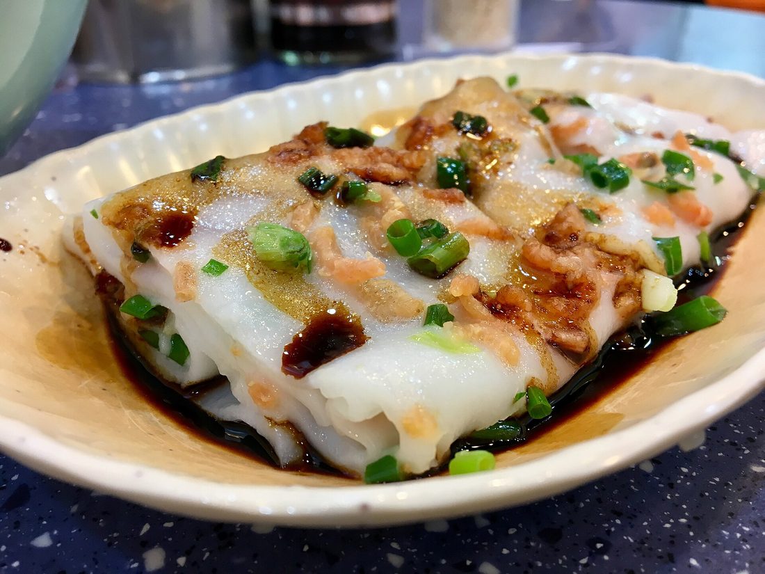 A spread of rice products — a bag of rice flour, dried rice vermicelli, a bottle of rice vinegar, mochi, rice paper wrappers, and puffed rice — everything rice becomes when it stops being a bowl of rice
