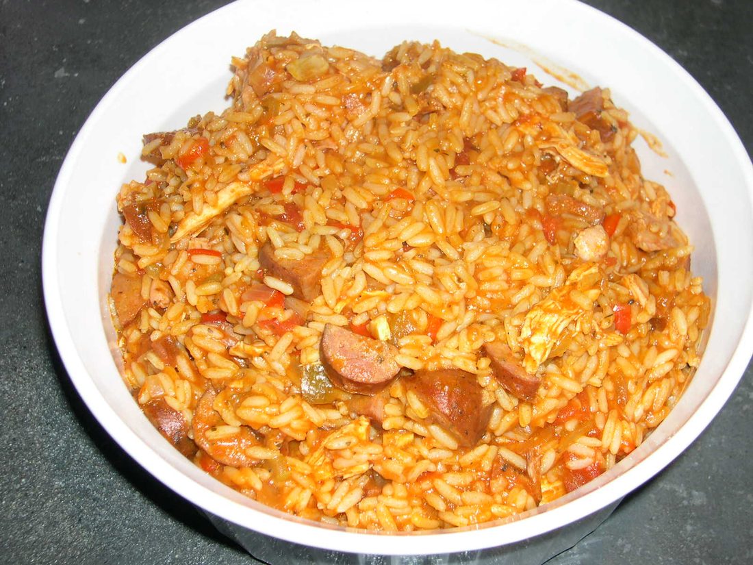 A cast-iron pot of Cajun jambalaya — brown, no tomato, studded with andouille and chicken, the rice cooked through and glossy with the fond scraped up from the bottom