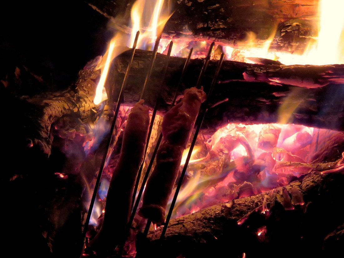 Linguiça over the fire at a Brazilian churrasco — the Portuguese fingerprint on South America's grill.