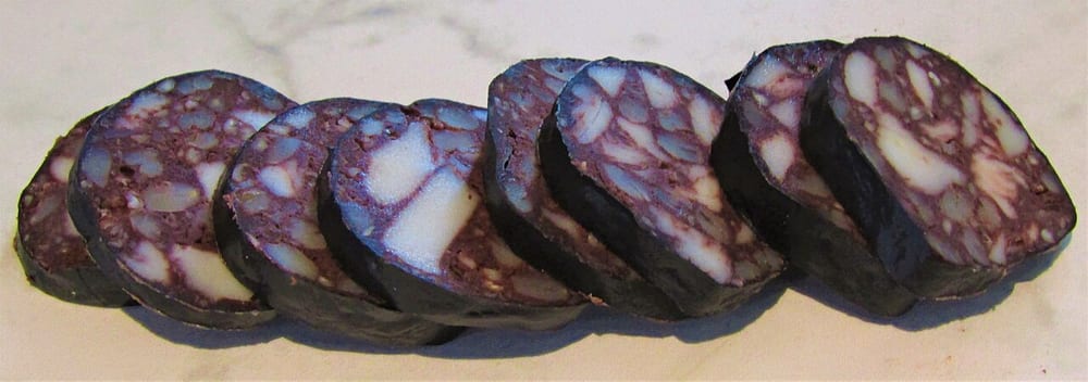 Slices of black pudding, the dark matrix set with distinct square white cubes of fat