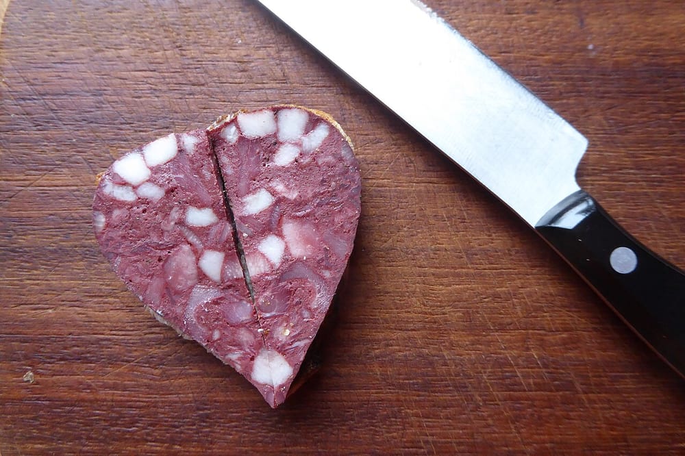 A slice of Blutwurst, its dark blood-and-meat matrix set with distinct cubes of white fat