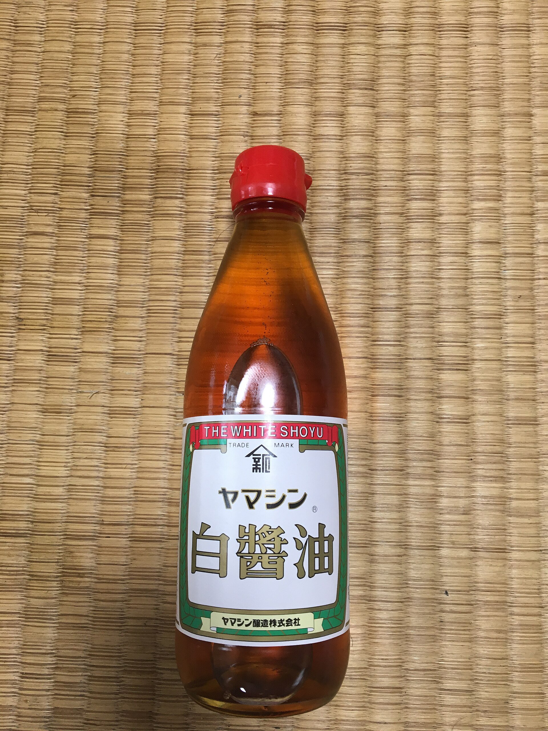 A bottle of Yamashin shiro shoyu, the liquid a clear pale amber like weak tea