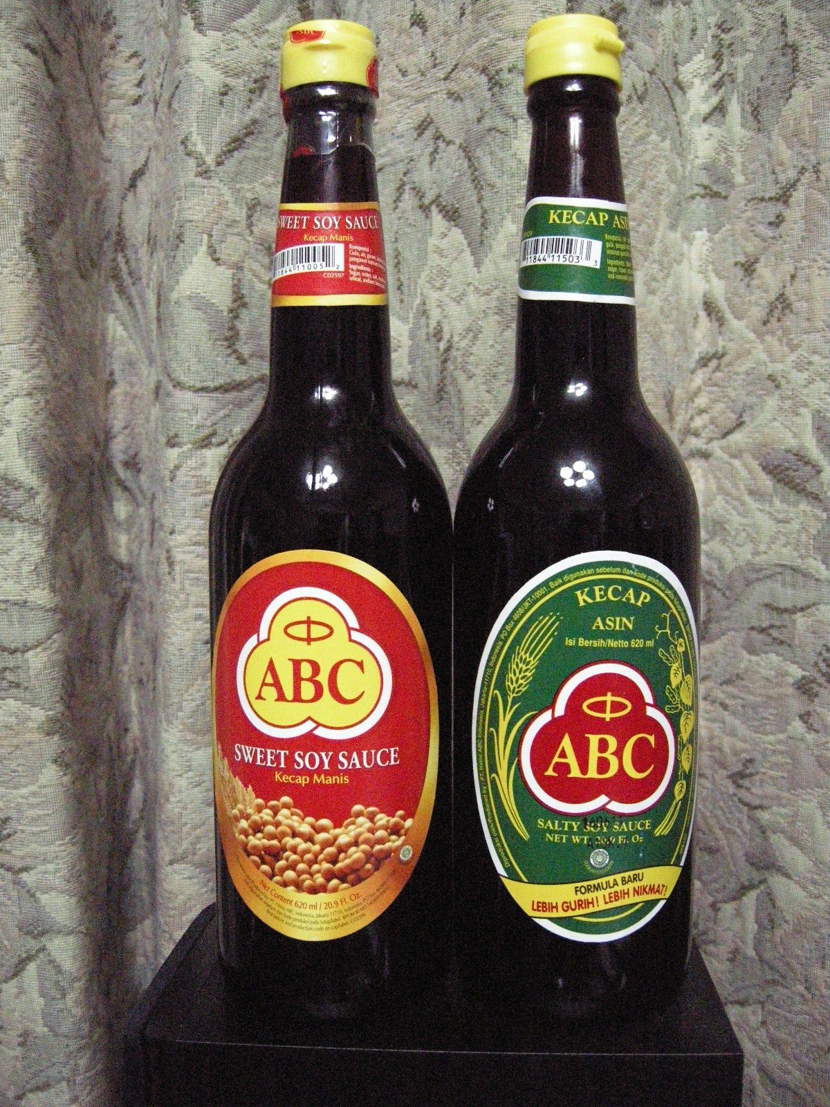 Two bottles of Indonesian ABC soy sauce side by side — kecap manis, sweet, and kecap asin, salty