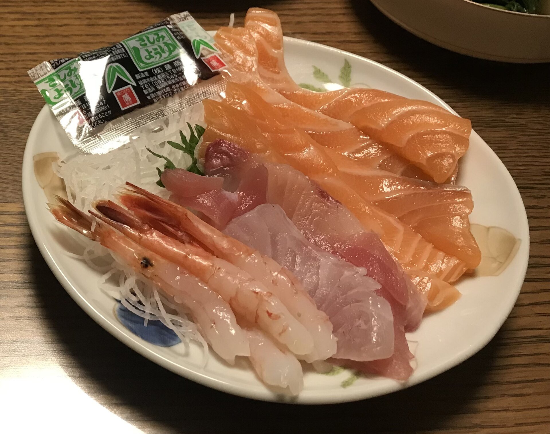 A plate of assorted sashimi with a small fish-shaped soy sauce packet