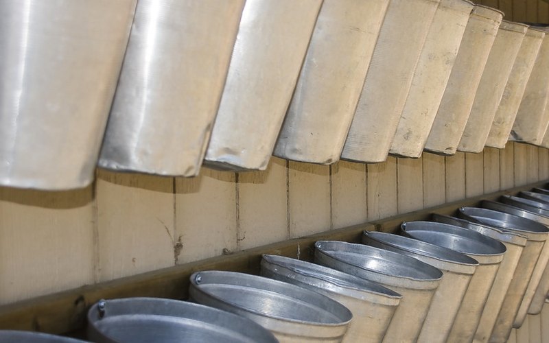 A rack of stored galvanized sap buckets with their lids stacked alongside, waiting for the season