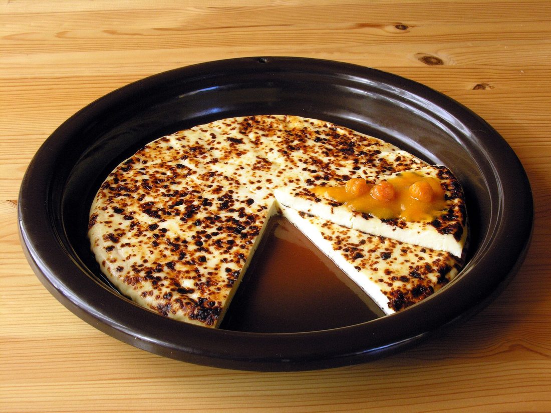 A round of Finnish leipäjuusto bread cheese with charred-brown freckles, sliced into wedges