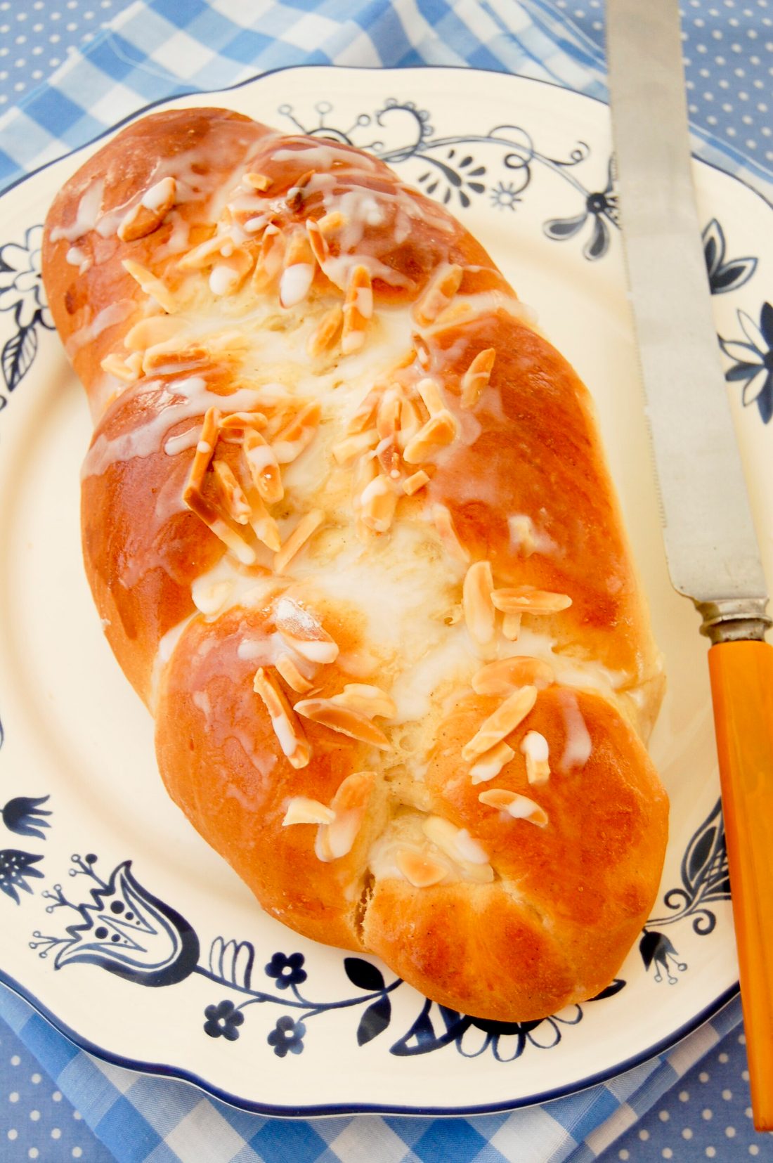A braided loaf of nisu (Finnish cardamom bread), glossy and topped with pearl sugar and almonds