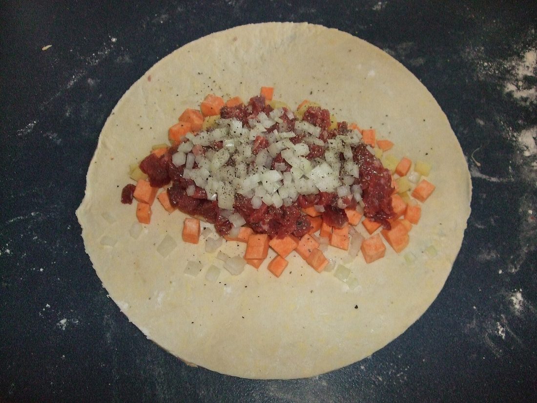 Diced pasty filling — beef, potato, onion and carrot — mounded raw on a rolled round of dough