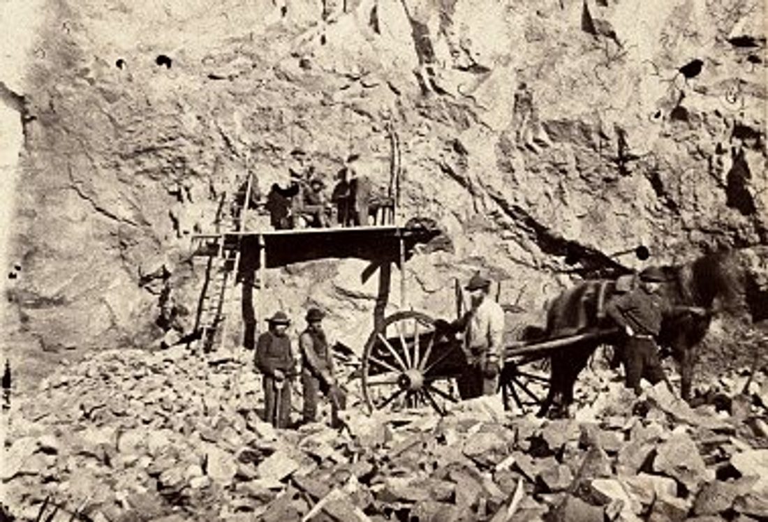 A black-and-white style photo of miners at a mine headframe in the Marquette Iron Range