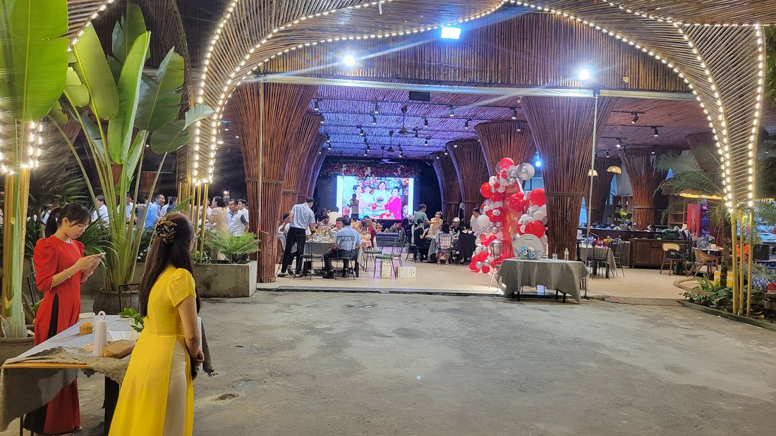 The same place at 18:54 — a covered hall the size of an aircraft hangar, strung with fairy lights, a stage at the far end and a balloon arch, with an event already under way